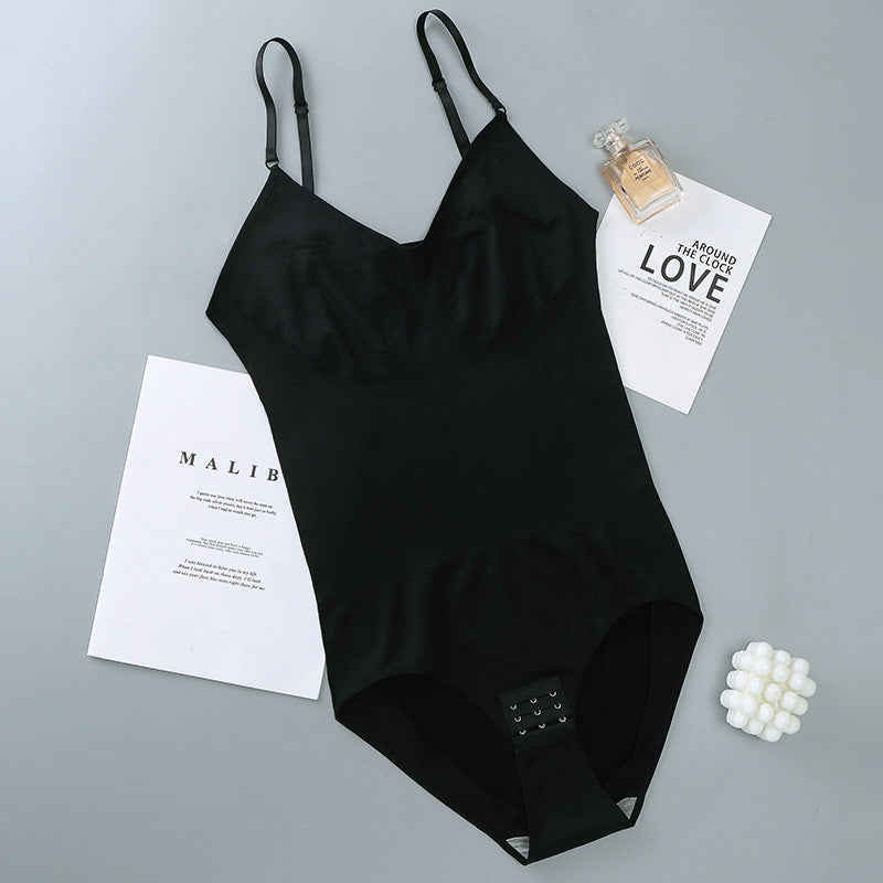 Black swimsuit on a gray surface with a bottle of perfume and papers.